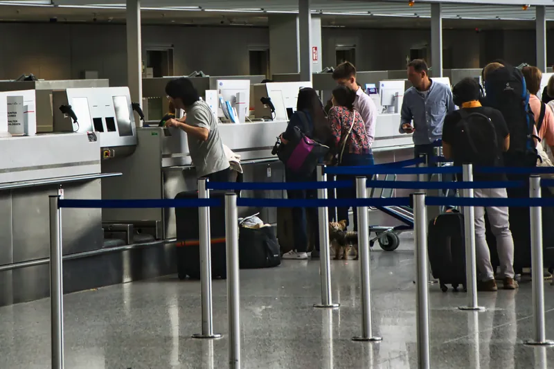 Reisende warten mit ihrem Gepäck in der Schlange vor den Check-in-Schaltern
