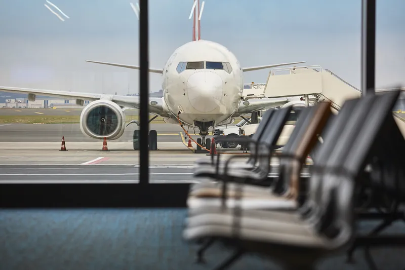 Verkehrsflugzeug steht vor der Glasfront eines Wartebereichs am Gate
