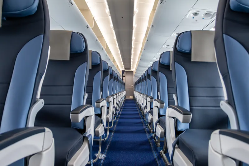 Blick durch den Gang einer leeren Flugzeugkabine mit blauen Sitzen