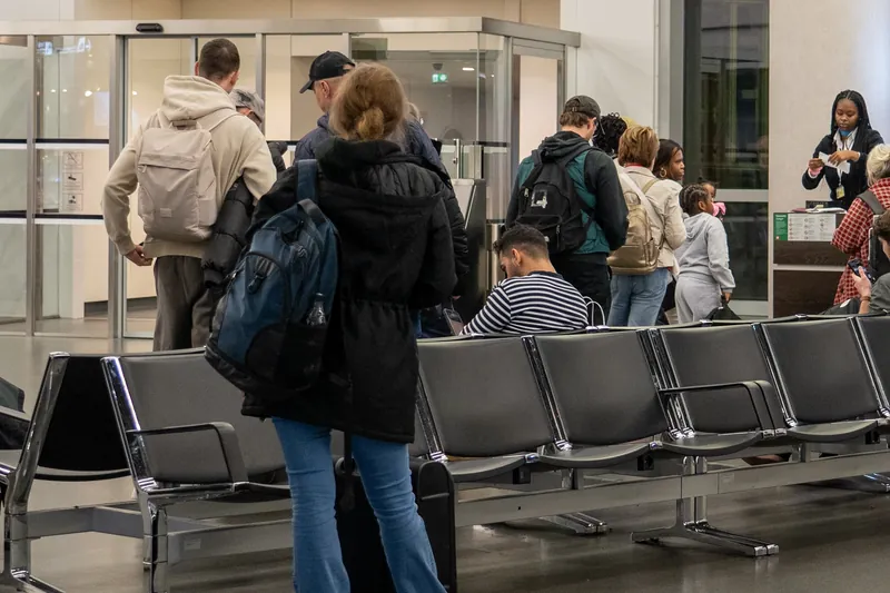 Reisende mit Rucksäcken warten im Wartebereich vor einem Gate
